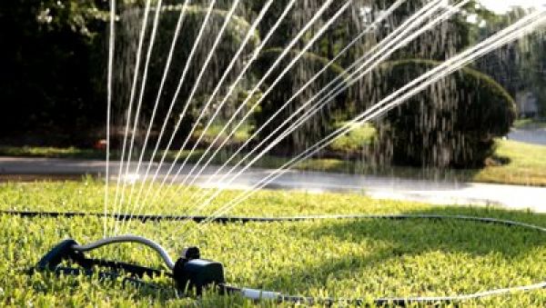 stock-footage-a-lawn-sprinkler-wasting-water-by-not-only-watering-a-parched-lawn-but-the-driveway-as-well