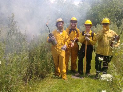 A group of people in protective gear at a controlled burn.